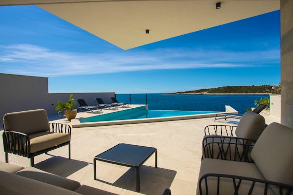 Spacious terrace with swimming pool, sundeck and lounge zone overlooking the sea